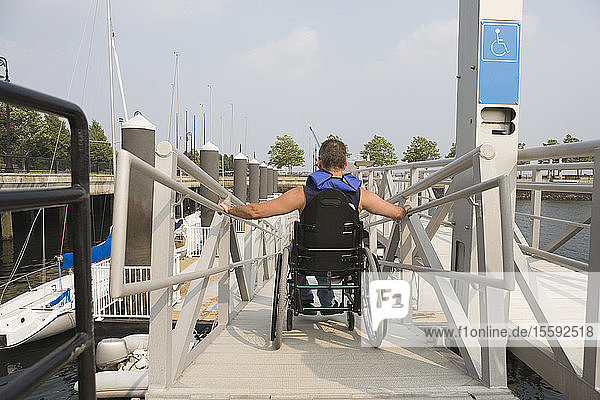 Rear view of a man sitting in a wheelchair on a wheelchair ramp