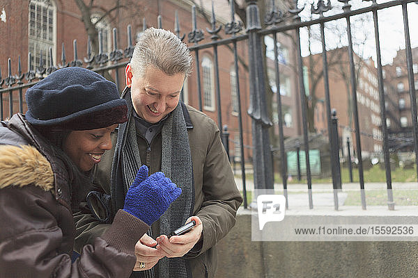Couple looking at pictures on a cell phone along Tremont Street and The Granary Burying Ground Historic site  Boston  Suffolk County  Massachusetts  USA