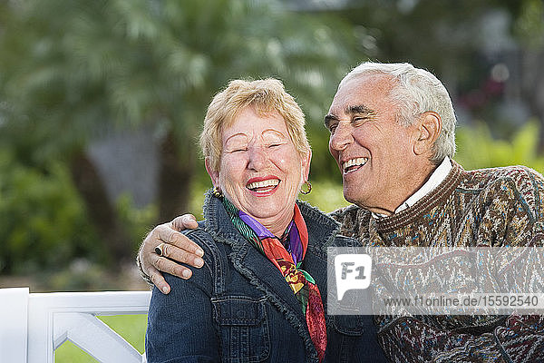 Blick auf ein lächelndes Seniorenpaar in einem Park.