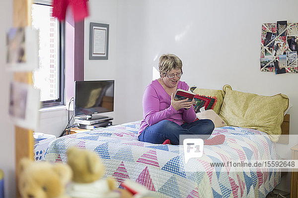 Frau mit Autismus sitzt auf dem Bett und liest ein Buch