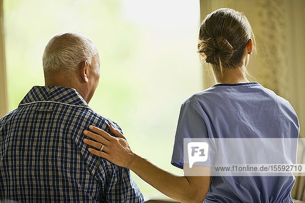 Nurse puts a reassuring hand on the back of a man.