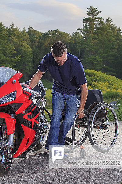 Mann mit Querschnittslähmung wechselt von seinem adaptiven Motorrad in seinen Rollstuhl