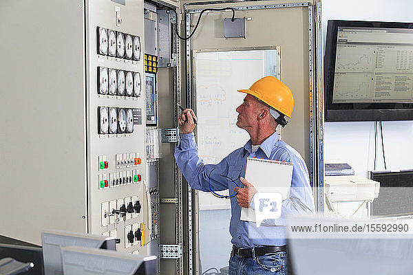 Electrical engineer inspecting power plant controls in central operations room of power plant