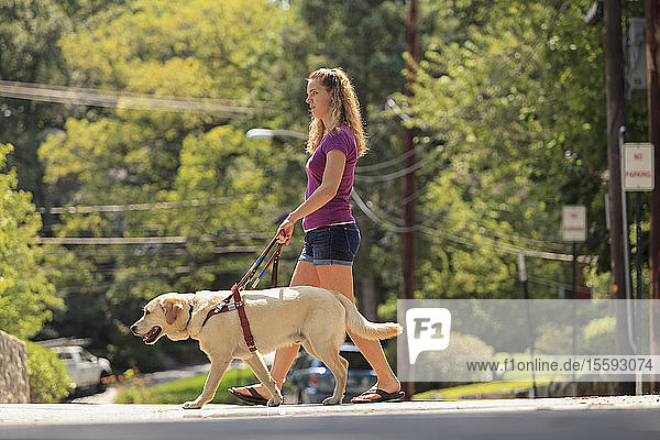 Studentin mit Sehbehinderung und ihr Diensthund beim Überqueren der Straße