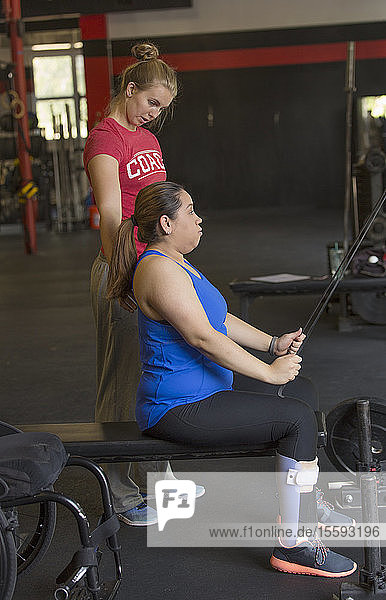 Frau mit Rückenmarksverletzung trainiert in einem Fitnessstudio mit einem Trainer