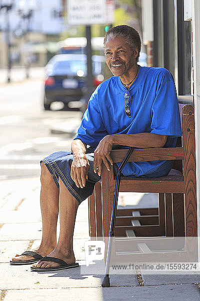 Mann mit traumatischer Hirnverletzung entspannt sich mit seinem Stock in der Nähe der Stadtstraße