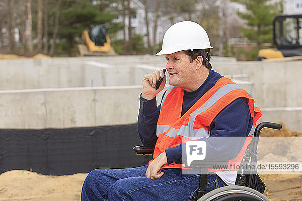 Construction engineer with spinal cord injury on radio at foundation site