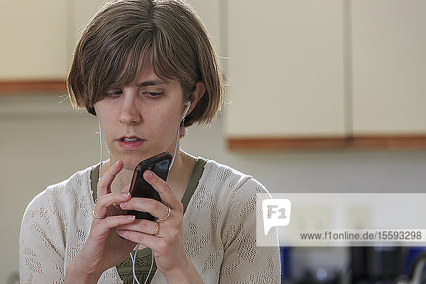 Blind woman using assistive technology ear plugs to listen to her cell phone