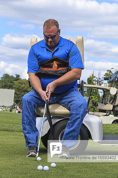 Mann mit Rückenmarksverletzung in einem adaptiven Wagen beim Golfspielen