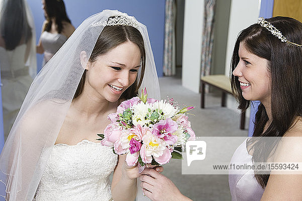 Braut mit ihrer Brautjungfer  die einen Blumenstrauß hält.
