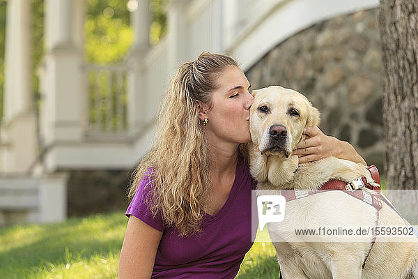 Frau mit Sehbehinderung küsst ihren Diensthund