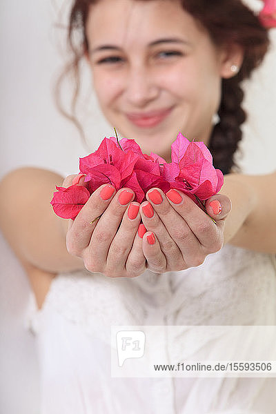 Lächelnde junge Frau mit Blumenblättern in den Händen
