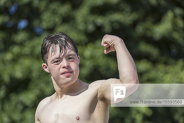 Portrait of young man with Down Syndrome showing his bicep on a dock