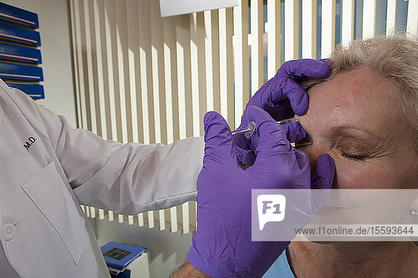 Augenarzt gibt einem Patienten eine Botox-Injektion
