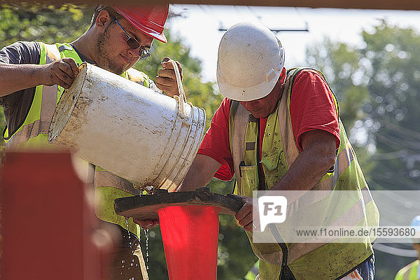 Bauarbeiter gießen Wasser  um eine Pumpe anzusaugen
