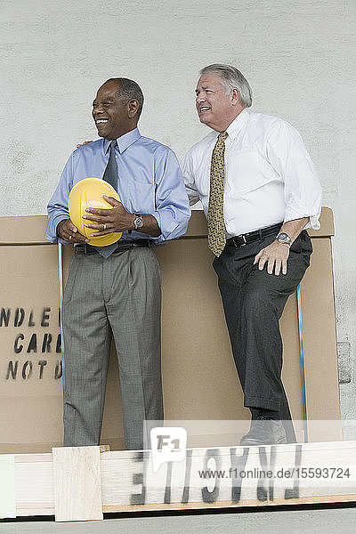 Two engineers standing near a cardboard box and smiling