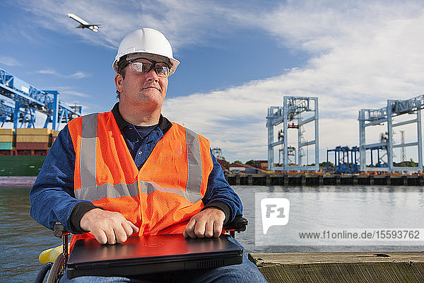 Transportingenieur im Rollstuhl mit einem Laptop im Verschiffungshafen