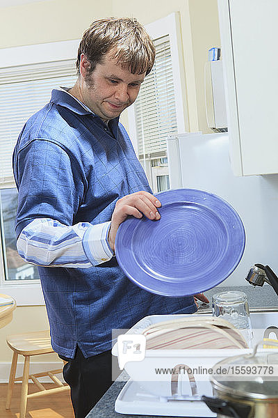 Mann mit Asperger-Syndrom lebt in seinem Haus und wäscht Geschirr