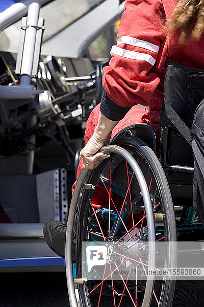 Frau steigt aus dem Rollstuhl auf den Fahrersitz eines Rennwagens  Nahaufnahme