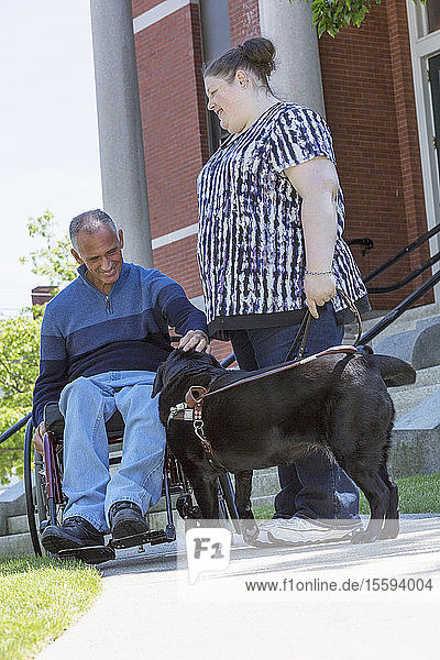 Ein Mann mit einer Rückenmarksverletzung und seine blinde Tochter mit einem Diensthund