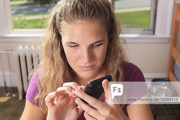 Studentin mit Sehbehinderung benutzt ihr Mobiltelefon in ihrem Wohnheimzimmer