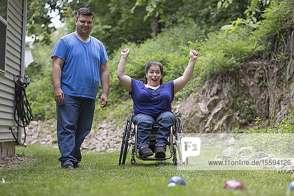 Frau mit Spina Bifida im Rollstuhl spielt Bocciaball mit ihrem Mann
