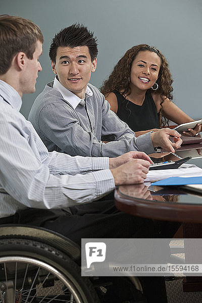 Visually impaired Hispanic businesswoman with two businessmen in an office