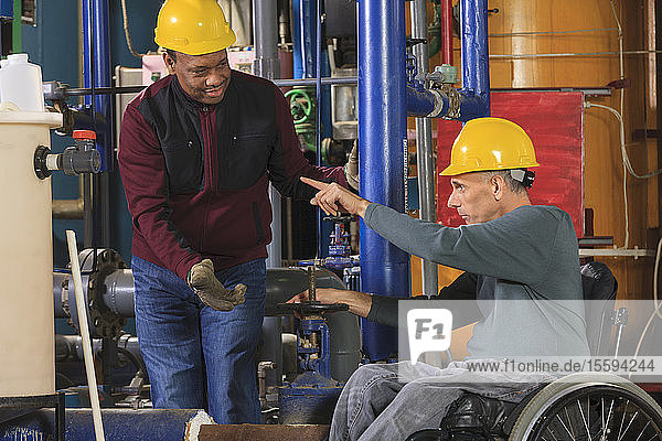 Power plant engineers one with spinal cord injury discussing valve settings