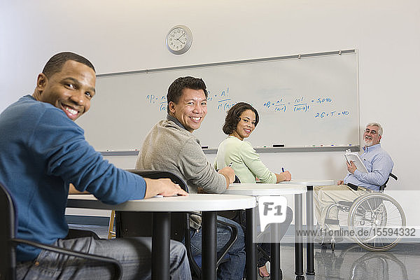 Universitätsprofessor mit Muskeldystrophie und Studenten in einem Klassenzimmer