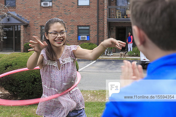Ein lernbehindertes Mädchen spielt Hula-Hoop-Reifen mit ihrem Bruder