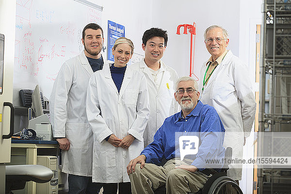 Engineering professors one with muscular dystrophy and students in chemical analysis laboratory