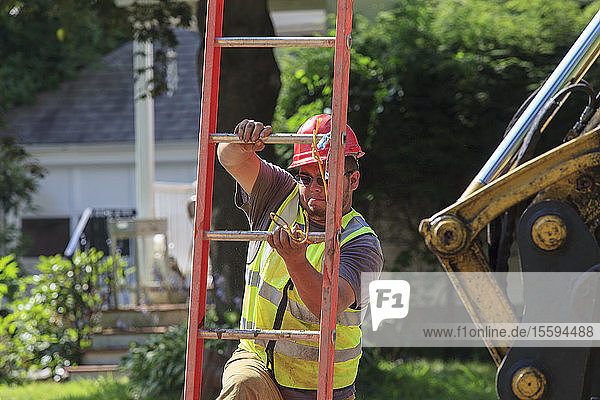 Bauarbeiter klettert über eine Leiter in einen Verbau