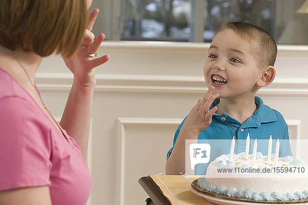 Woman signing the word 'Birthday' in American sign language while communicating with her son