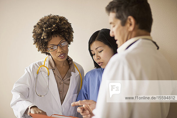 Drei Ärzte besprechen Patientenakten in einem Korridor