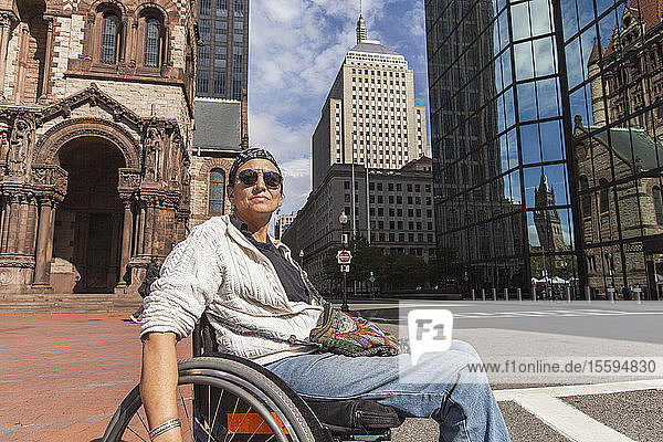 Woman with spinal cord injury crossing street St. James Avenue John Hancock Tower Trinity Church Boston Massachusetts USA