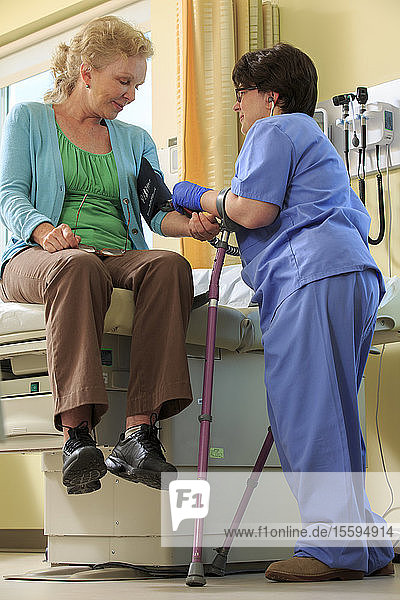 Krankenschwester mit Zerebralparese misst den Blutdruck eines Patienten in einer Klinik