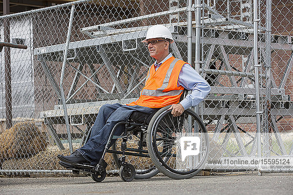 Projektingenieur mit einer Rückenmarksverletzung in einem Rollstuhl auf der Baustelle