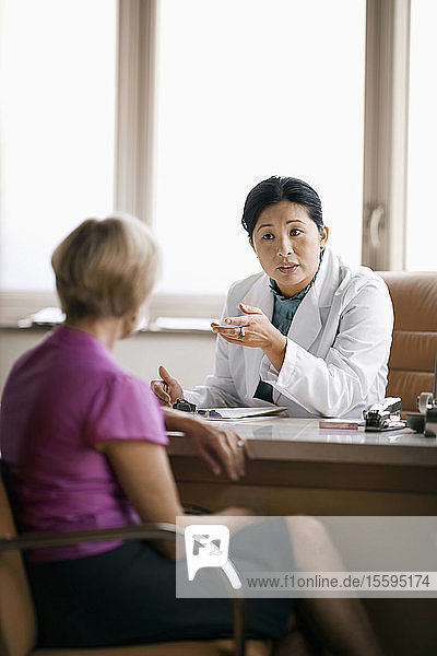 Friendly mid adult doctor consulting with a patient in her office