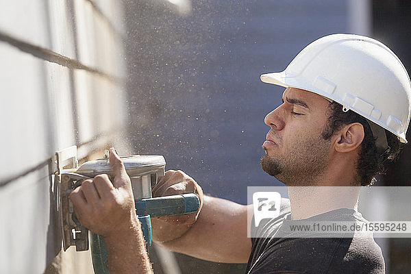Hispanic-Zimmermann trimmt Hausverkleidung für die Installation einer neuen Terrasse