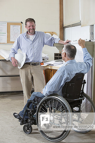 Zwei Projektingenieure im Gespräch über ihre Arbeit  einer im Rollstuhl mit einer Rückenmarksverletzung