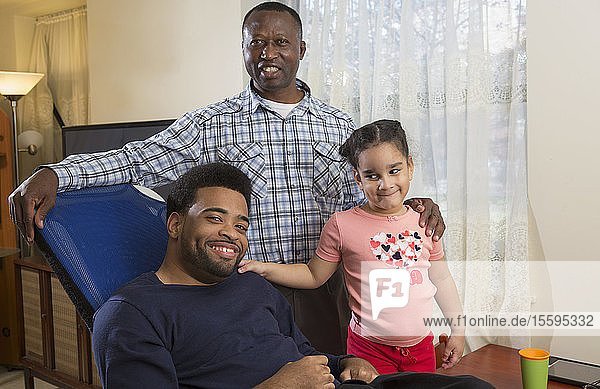 African American man with Cerebral Palsy with his daughter and Personal Care Assistant at home