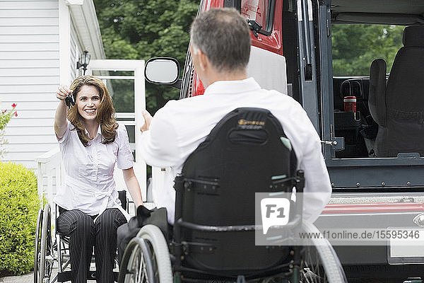 Mid adult woman giving a car key to a mid adult man sitting in a wheelchair with a Spinal Cord Injury