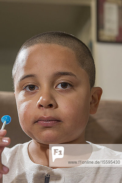 Porträt eines hispanischen Jungen mit Autismus  der einen Lollypop isst