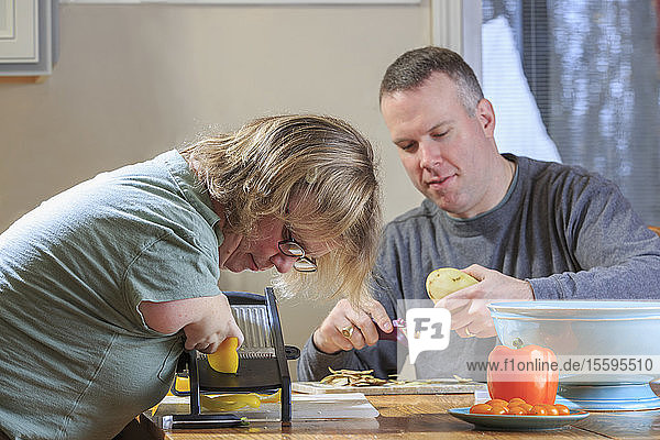 Frau mit TAR-Syndrom reibt mit ihrem Mann in der Küche Gemüse