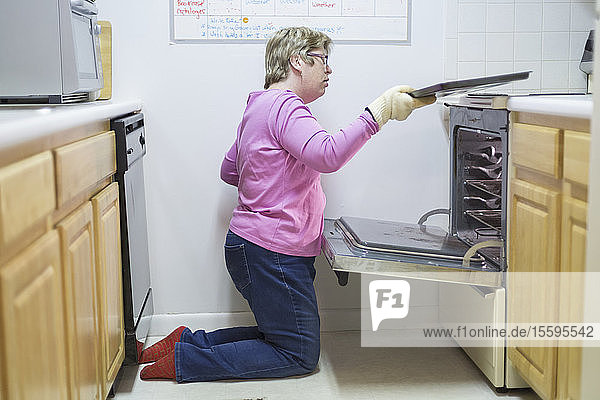 Frau mit Autismus nimmt Tablett aus dem Ofen
