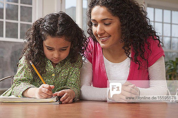 Hispanic woman assisting her daughter while doing homework