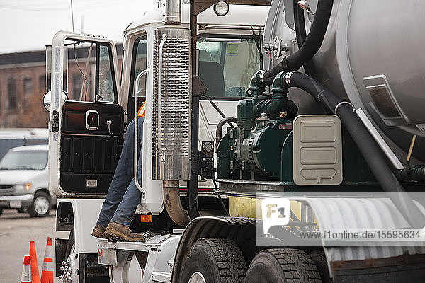 Umwelttechniker greift in die Fahrerseite eines Tankwagens  um gefährliche Abfälle zu beseitigen