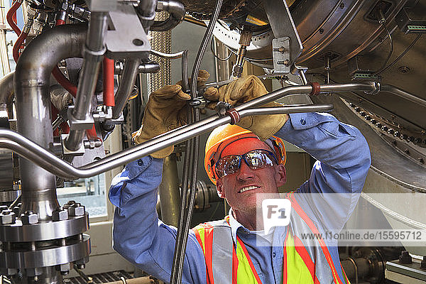 Engineer under ignitor stage of gas turbine which drives generators in power plant while turbine is powered down