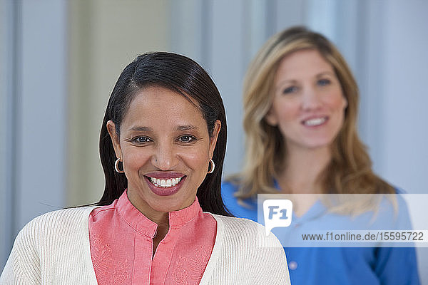 Portrait of a Hispanic woman smiling with her friend in the background