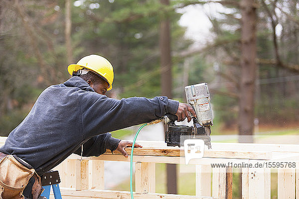Carpenter using a nail gun to frame house